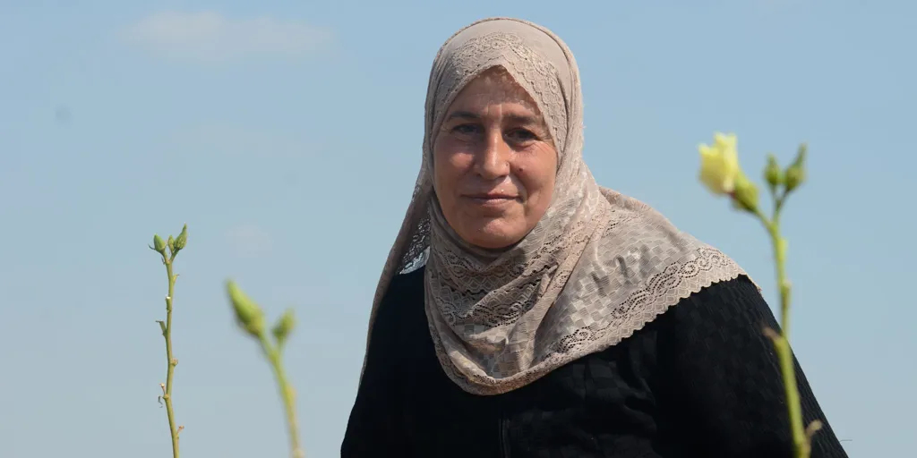 Portrait of Syrian refugee Layla amongst okra flowers.