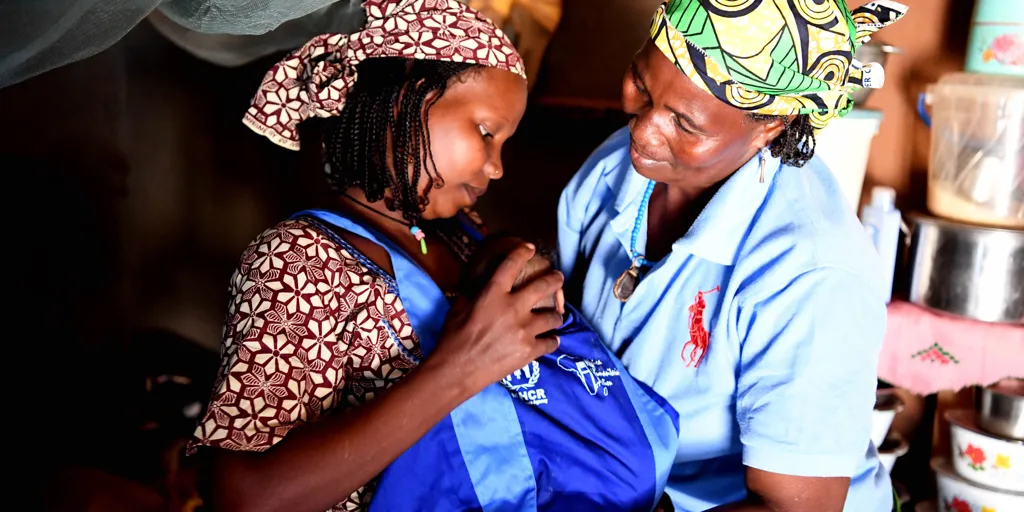 A woman helps her daughter in law with the kangaroo scarf in Cameroon.